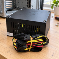 Fuente de poder ATX Unitec 750W para computador — fuente en mesa de reparación con cables apoyados